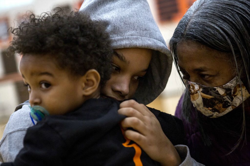 Third Place, Sports Picture Story - Jessica Phelps / Newark Advocate, “Coaching Creates Deep Roots For Croom Family”Taliyah Holmes holds her baby brother, Kendrix while her great-grandmother, Ruby Stinson comes over to congratulate her on her first basketball of the season, November 21, 2020. Ruby, who is the matriarch of the family raised 6 children by herself in the Heath area. Ruby is the reason the entire extended family is always there to support each other whether at  children games or through the tough times. She is the reason all the women in the family have so much inner strength and self confidence. The roots Ruby established in the area is also a large part of why this Black family has choses to stay in a largely white, conservative area when so many other Black families have left. 